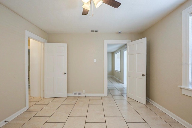 empty room featuring light tile patterned floors, baseboards, and visible vents