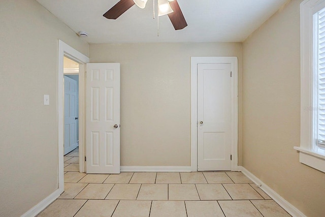 spare room with light tile patterned flooring, ceiling fan, and baseboards