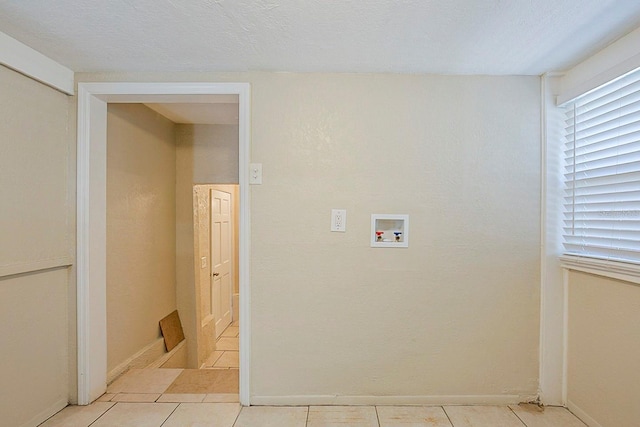 clothes washing area featuring a textured ceiling, light tile patterned flooring, baseboards, hookup for a washing machine, and laundry area