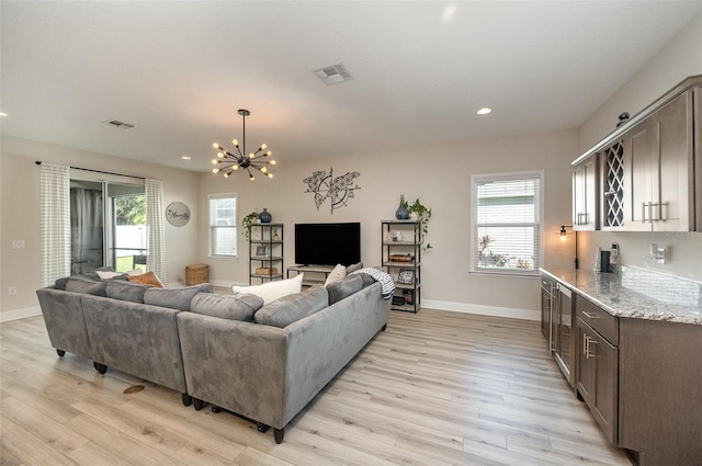 living room featuring light wood-style floors, visible vents, and baseboards