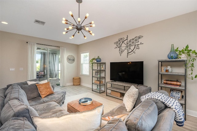 living room featuring light wood finished floors, baseboards, visible vents, and a notable chandelier