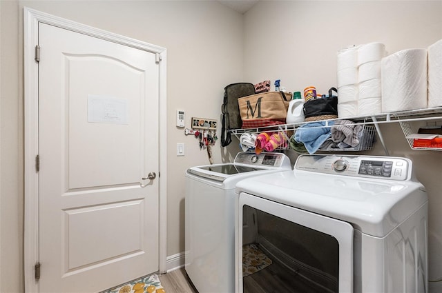 laundry room with laundry area, light wood finished floors, washing machine and dryer, and baseboards