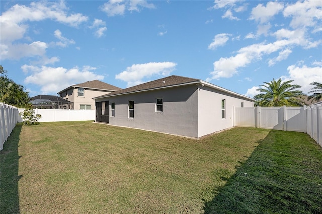 rear view of house featuring a yard, a fenced backyard, a gate, and stucco siding