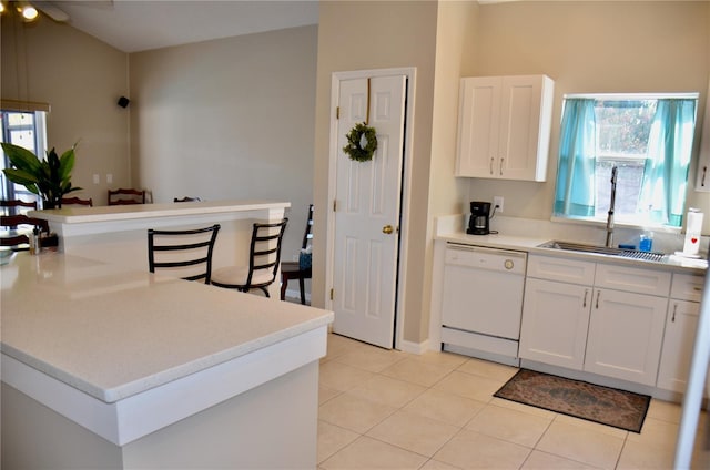 kitchen featuring light tile patterned floors, light countertops, white cabinets, a sink, and dishwasher