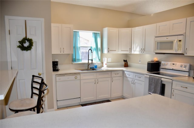 kitchen with light countertops, white appliances, white cabinets, and a sink