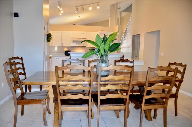 dining space featuring vaulted ceiling, baseboards, and light tile patterned floors