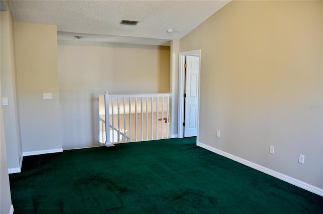 unfurnished room featuring baseboards, visible vents, dark carpet, and a textured ceiling