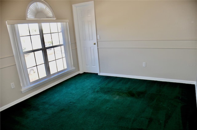 unfurnished room featuring baseboards and dark carpet