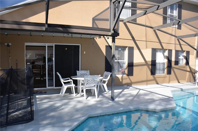 exterior space featuring stucco siding, outdoor dining space, a patio area, a lanai, and an outdoor pool