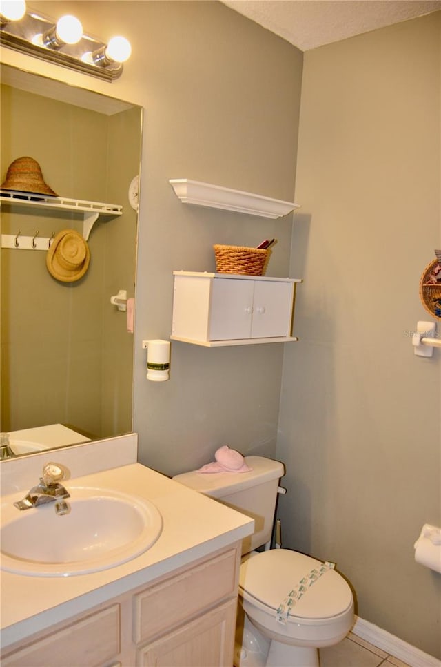 bathroom featuring vanity, tile patterned flooring, toilet, and baseboards