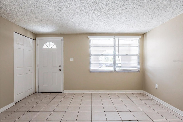 foyer featuring a textured ceiling, baseboards, and light tile patterned floors