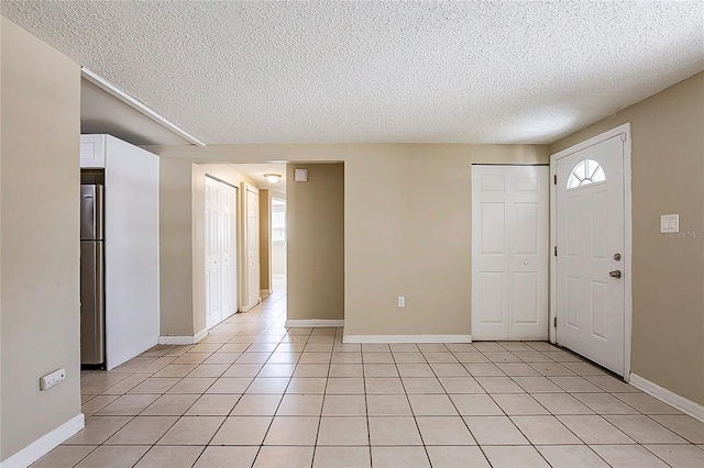 entrance foyer featuring light tile patterned floors, a textured ceiling, and baseboards