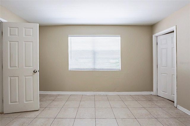 empty room with light tile patterned floors and baseboards