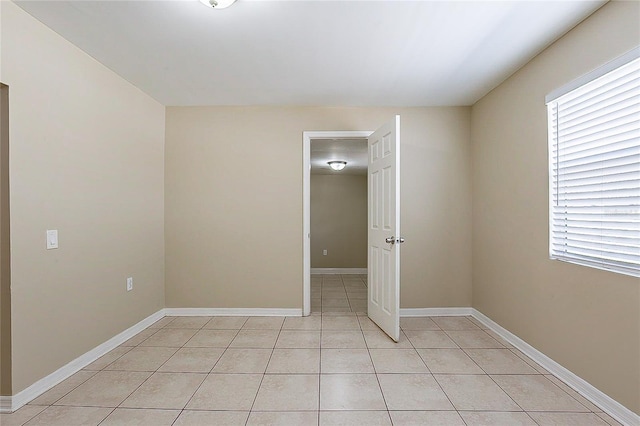 empty room featuring light tile patterned flooring and baseboards