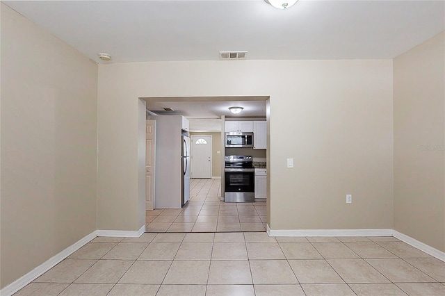 spare room featuring light tile patterned floors, visible vents, and baseboards