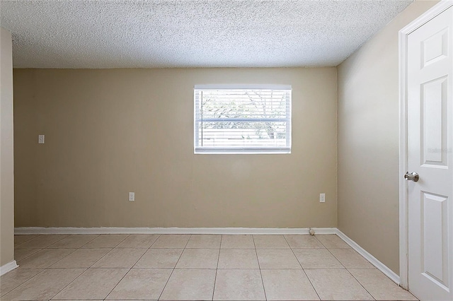 unfurnished room with a textured ceiling, baseboards, and light tile patterned floors