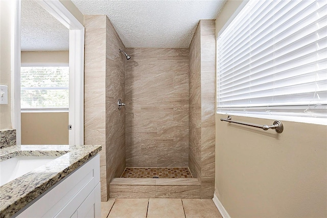 full bathroom featuring tile patterned flooring, tiled shower, a textured ceiling, and vanity