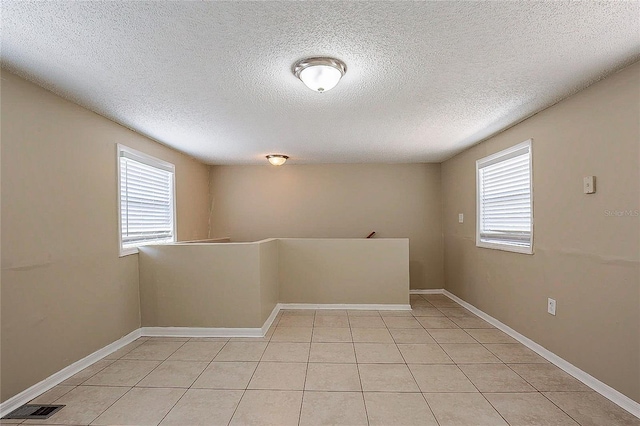 unfurnished room with a healthy amount of sunlight, visible vents, baseboards, and light tile patterned flooring