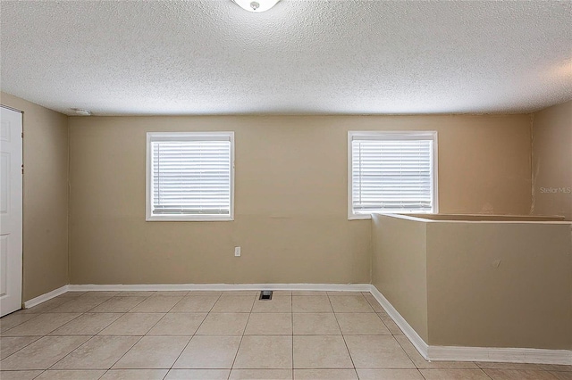 unfurnished room with light tile patterned floors, plenty of natural light, and baseboards