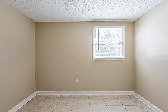 unfurnished room with light tile patterned floors, baseboards, and a textured ceiling