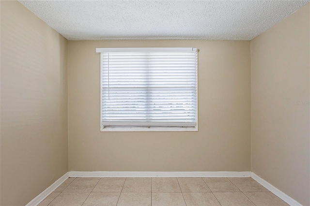 unfurnished room featuring light tile patterned flooring, a textured ceiling, and baseboards