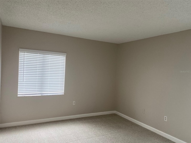 unfurnished room with carpet floors, a textured ceiling, and baseboards