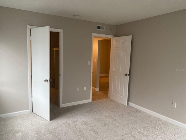 unfurnished bedroom with carpet floors, visible vents, and baseboards