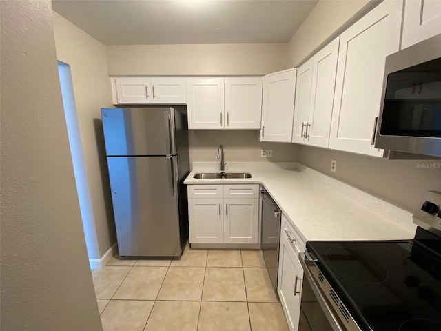 kitchen with appliances with stainless steel finishes, light countertops, white cabinetry, and a sink