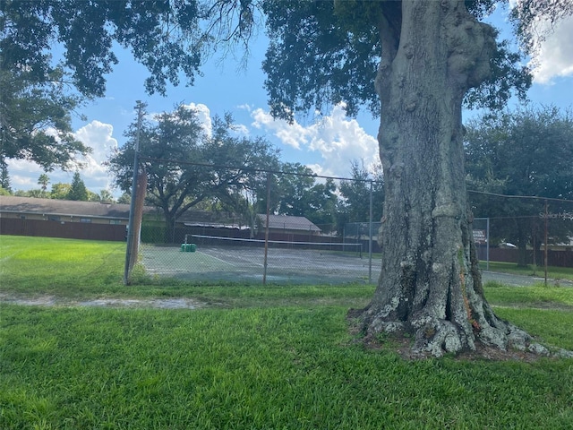 exterior space with a tennis court and fence