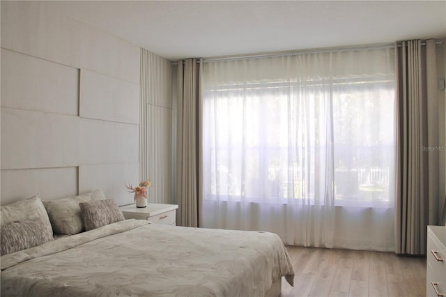 bedroom with light wood finished floors and multiple windows