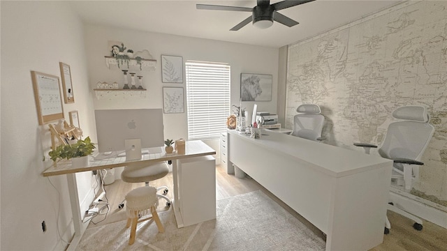 home office with an accent wall, a ceiling fan, and wallpapered walls