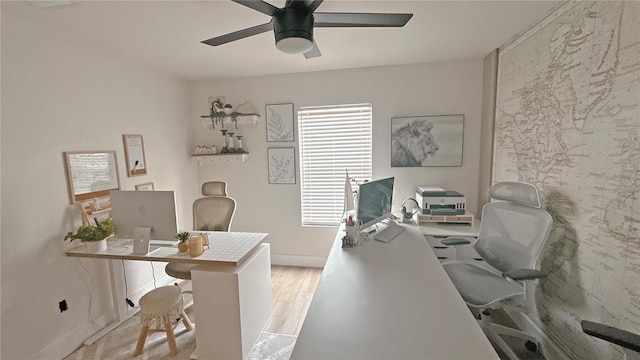 office space with a ceiling fan, baseboards, and light wood finished floors