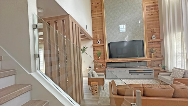 living area with a towering ceiling, stairs, and wood finished floors