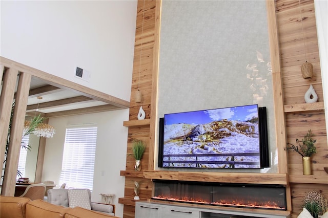 living room with a towering ceiling, a fireplace, visible vents, and beam ceiling