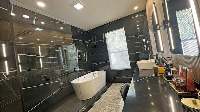 full bathroom with a freestanding bath, double vanity, tile walls, and recessed lighting