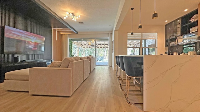 living area featuring visible vents, a textured ceiling, and light wood finished floors