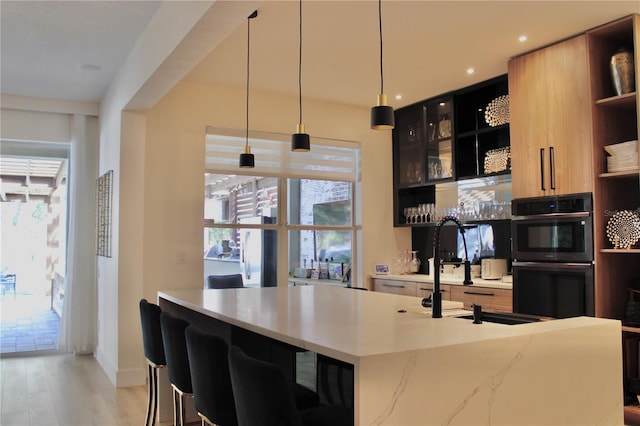 kitchen with pendant lighting, double wall oven, open shelves, glass insert cabinets, and light wood-type flooring