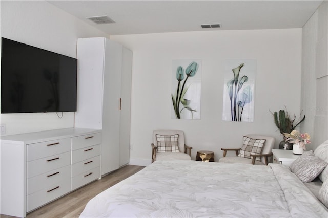 bedroom with light wood-style floors and visible vents