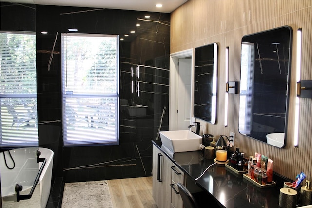 bathroom featuring double vanity, a bathtub, a sink, and wood finished floors