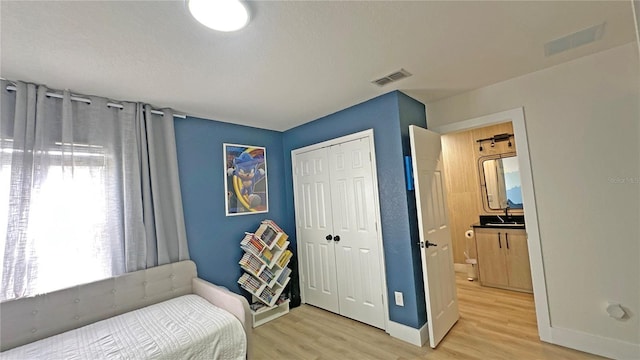 bedroom featuring a closet, visible vents, baseboards, and wood finished floors