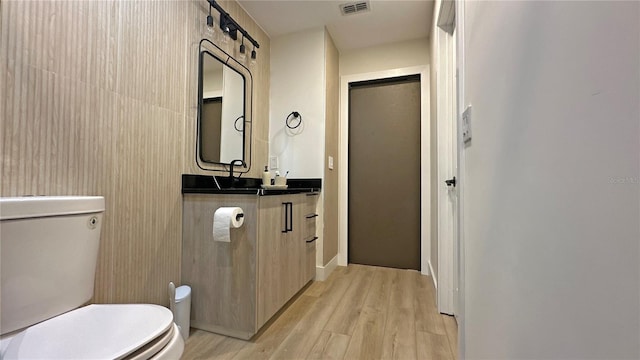 bathroom featuring visible vents, vanity, wood finished floors, and toilet