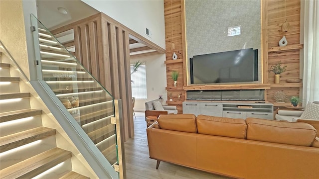 living area with a high ceiling, light wood-style floors, stairs, and visible vents