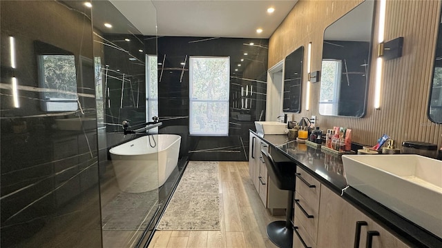 bathroom featuring wood finished floors, a stall shower, a freestanding tub, and vanity