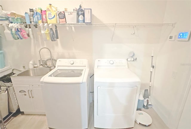 washroom with a sink, cabinet space, and washer and dryer