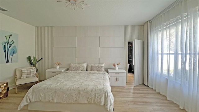 bedroom with light wood-style flooring, visible vents, and a textured ceiling