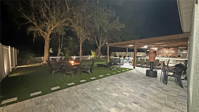 patio at twilight featuring an outdoor living space with a fire pit, a fenced backyard, and a yard