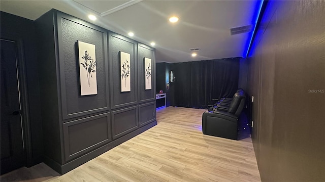 interior space with lofted ceiling, light wood-style floors, visible vents, and a decorative wall