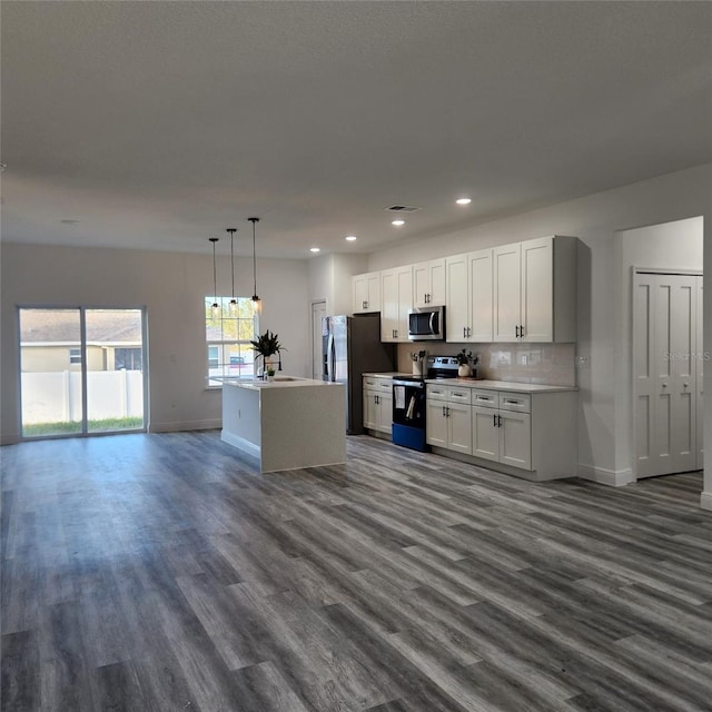 kitchen with open floor plan, hanging light fixtures, stainless steel appliances, light countertops, and white cabinetry