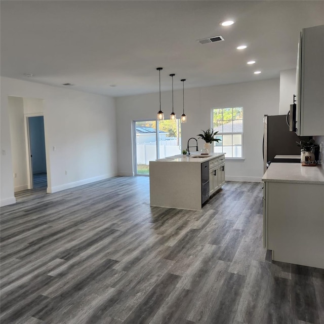 kitchen featuring a center island with sink, visible vents, open floor plan, hanging light fixtures, and light countertops