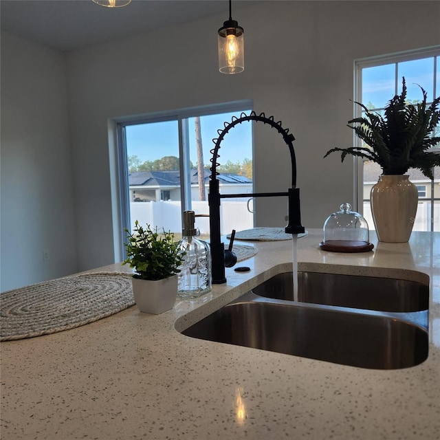 interior space with a sink, decorative light fixtures, and light stone countertops